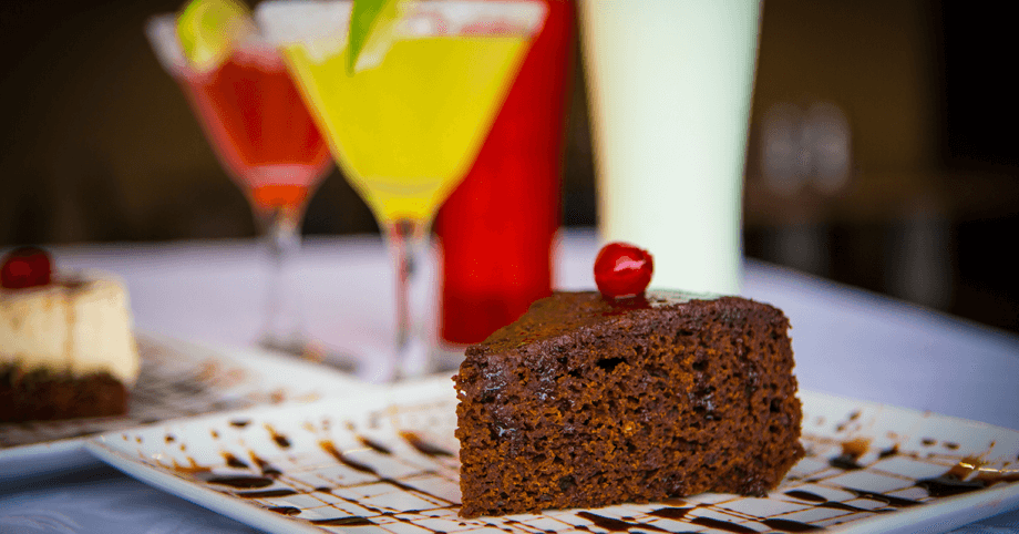 Traditional Jamaican rum cake with rum cocktails in the background