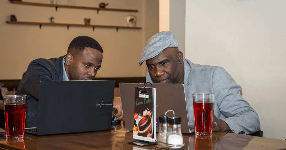 Two men having a business meeting over drinks, working on laptops in a relaxed setting