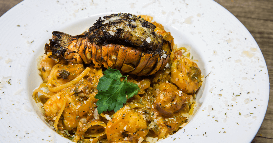 Luxurious seafood pasta topped with spicy jerked lobster tail in creamy rose sauce