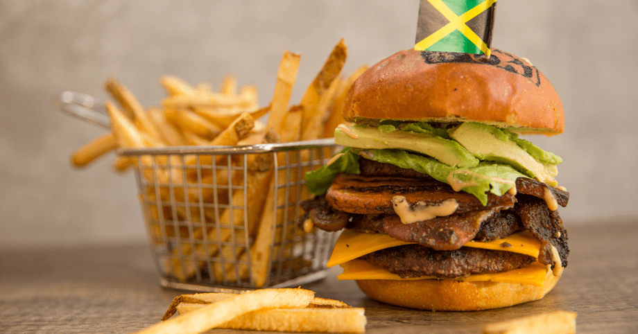 Delicious 'Yah Mon' beef burger topped with jerked bacon, cheddar, plantain, lettuce, and aioli