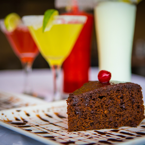 Jamaican rum cake with drinks in the background – thumbnail view