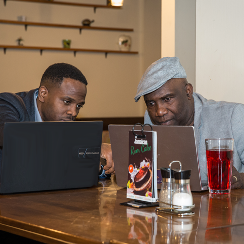 Two professionals enjoying drinks while working on laptops – thumbnail view
