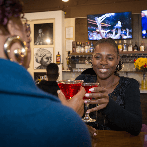 Two women enjoying cocktails while watching the game at the bar – thumbnail view